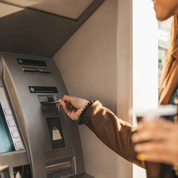 Woman getting money out of an ATM with her Peak Checking debit card from CCCU credit union in Portland Oregon.