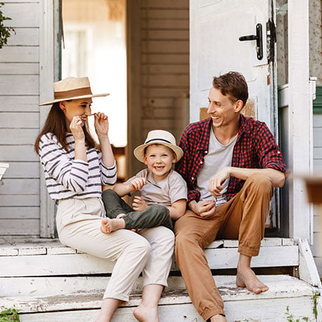 Cheerful family sitting on the porch of their new house after saving with First Time Homebuyer Savings Account at CCCU