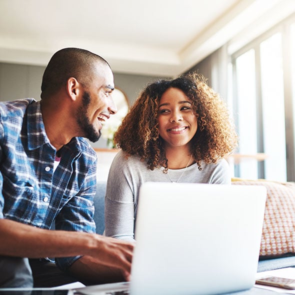 Young couple applying for an FHA loan on computer with home loan from CCCU local credit union in Portland Oregon.