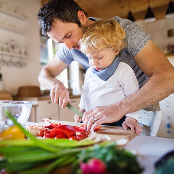 Father and son making a salad together in their new kitchen at home.