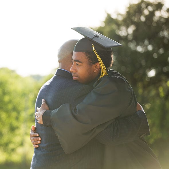 Father and son hugging at high school graduation.