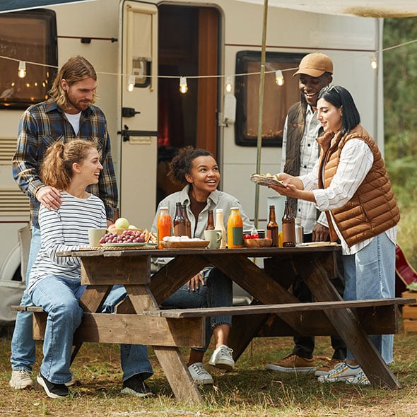 Group family camping and eating dinner outside of their RV purchased with an RV loan.
