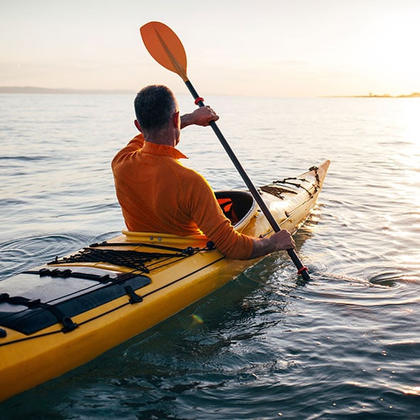 Man kayaking on vacation after reaching his savings goals with a CCCU savings account