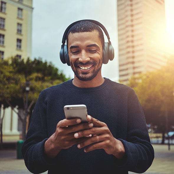 Man walking through the city, looking at his mobile checking account with CCCU credit union.