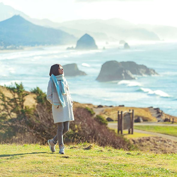 Woman on Oregon Coast walking and thinking about purchasing her first home and saving with a First Time Homebuyer Savings Account