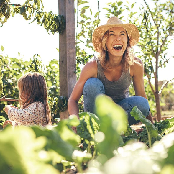 Woman garening in yard with her daughter after purchasing new home with CCCU mortgage home loan