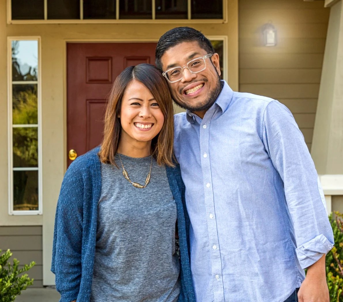 couple-smiling-in-front-of-house-min