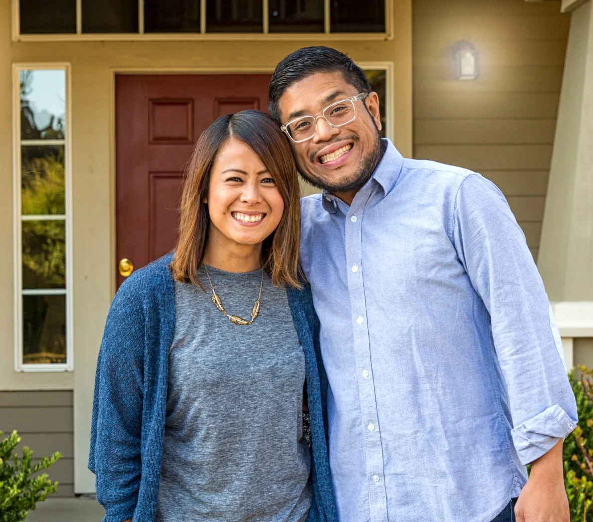 couple-smiling-in-front-of-house-min