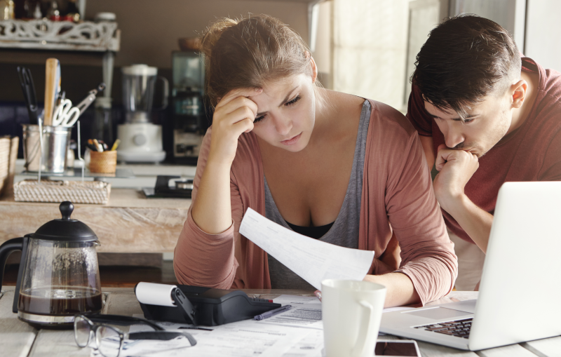 young married couple frustrated while paying their bills